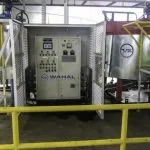 Wahal control panel in a mesh enclosure between storage tanks at a bitumen emulsion plant