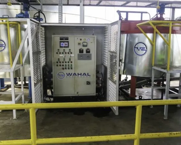 Wahal control panel in a mesh enclosure between storage tanks at a bitumen emulsion plant
