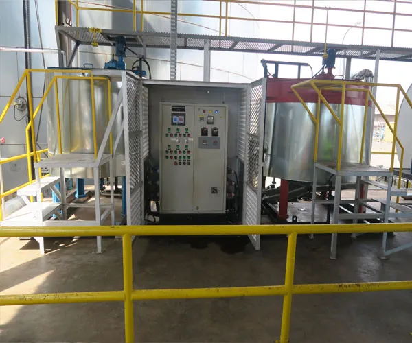 Control panel between two emulsion mixing tanks with yellow access platforms at a jute batching plant
