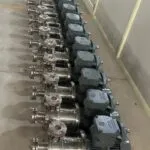 Row of a dozen inline homogenizers with grey motors lined up on a workshop floor